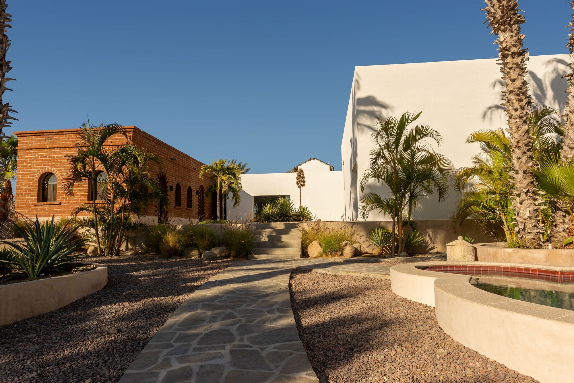 Flagstone path between the brick building and the white modernist volume