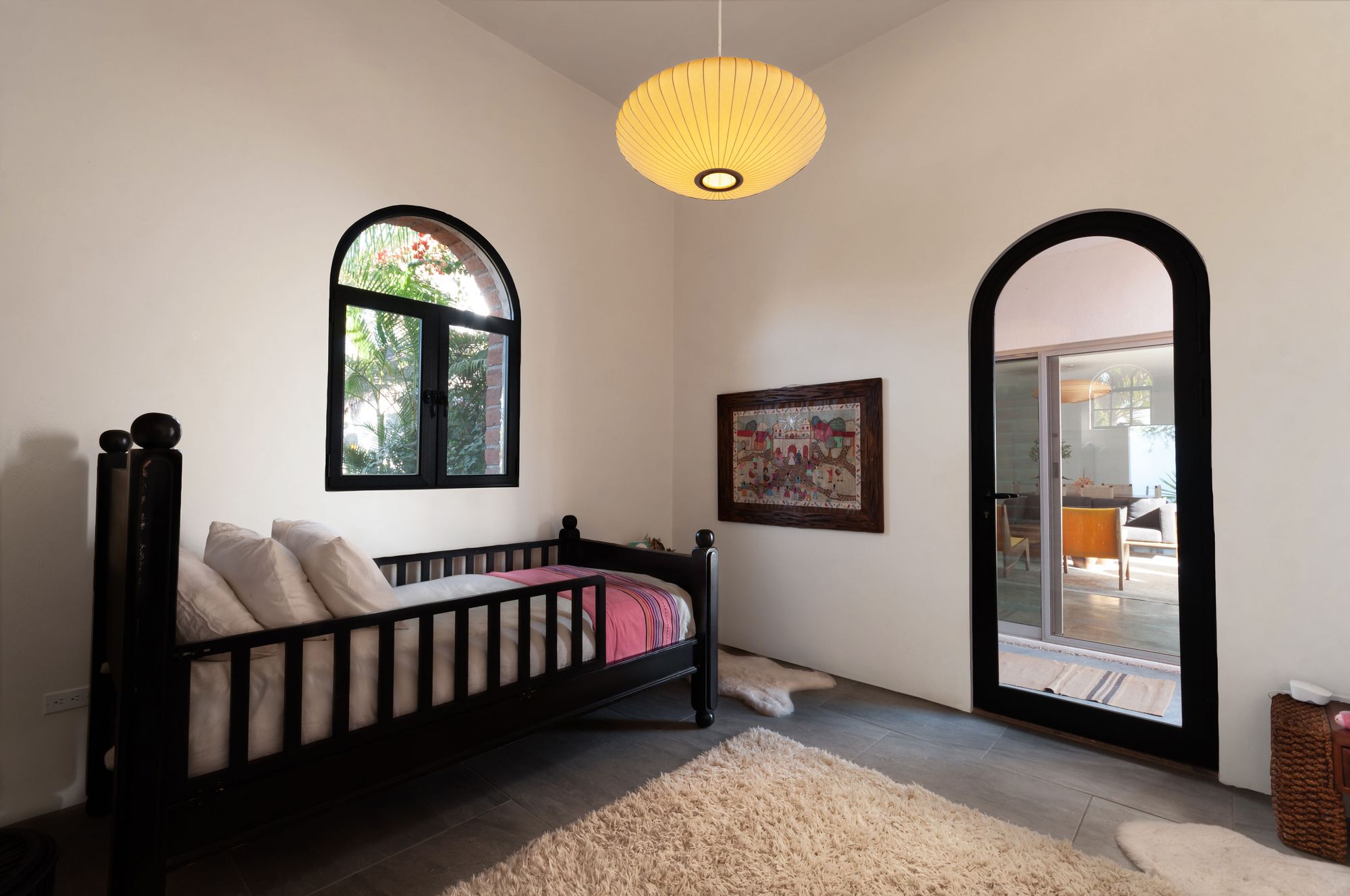 Guest room with a black daybed, paper lantern and arched glass door to the living area